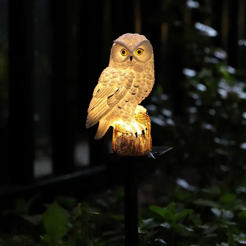 Weiße Eule mit gelben Augen leuchtet nachts warm von innen, sitzend auf einem Baumstumpf vor dunklem Hintergrund. 6
