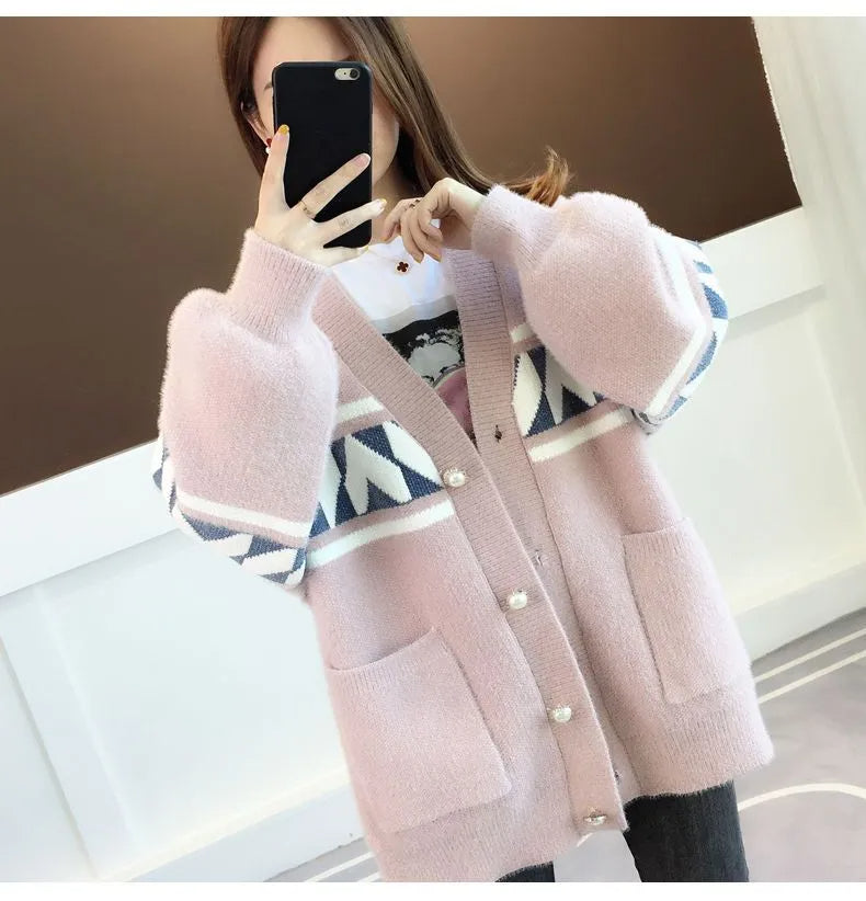 Frau trägt rosa Strickjacke mit geometrischem Muster, weiches Material, modisch, gemütlich.