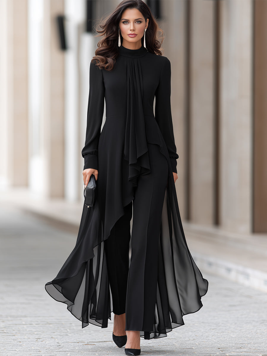 Ganzkörperansicht einer Frau in schwarzem Chiffon-Set aus Tunika mit drapiertem Halstuch und weiter Hose, dazu schwarze Pumps und Clutch. 2