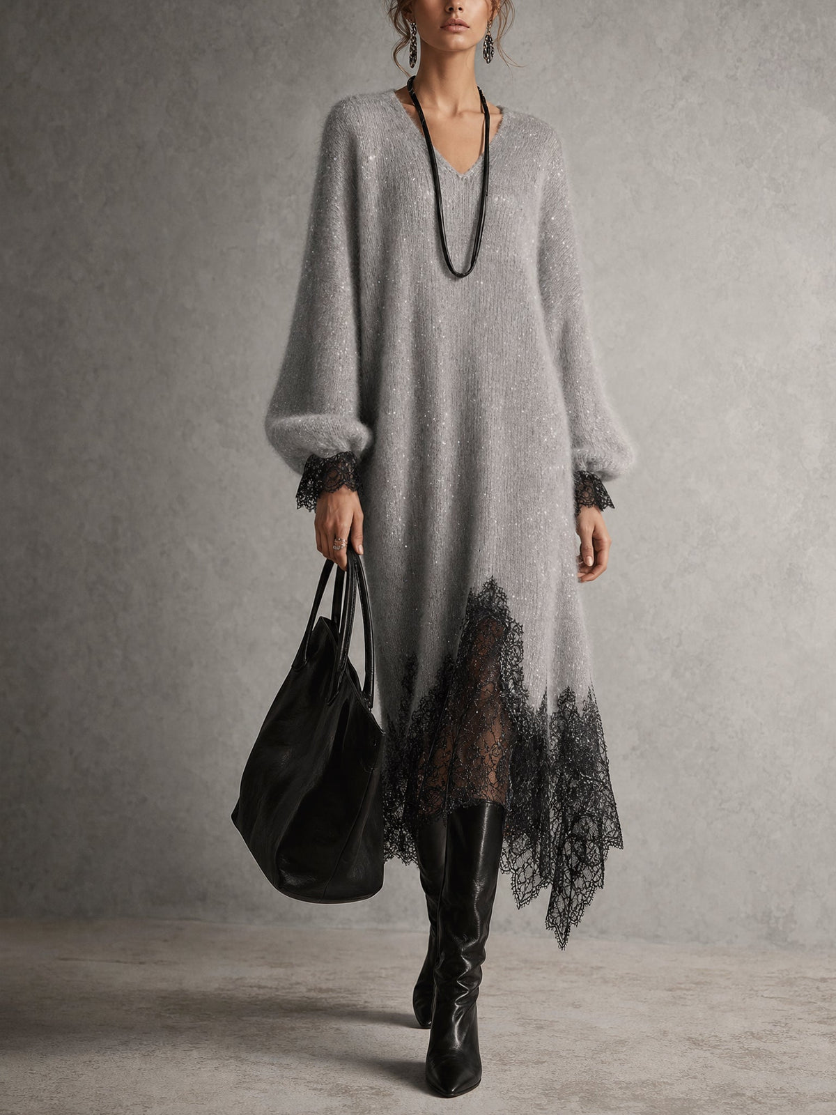 Model in grauem Strickkleid mit schwarzer Spitze am Saum, dazu schwarze Stiefel und Tasche, Frontansicht 1