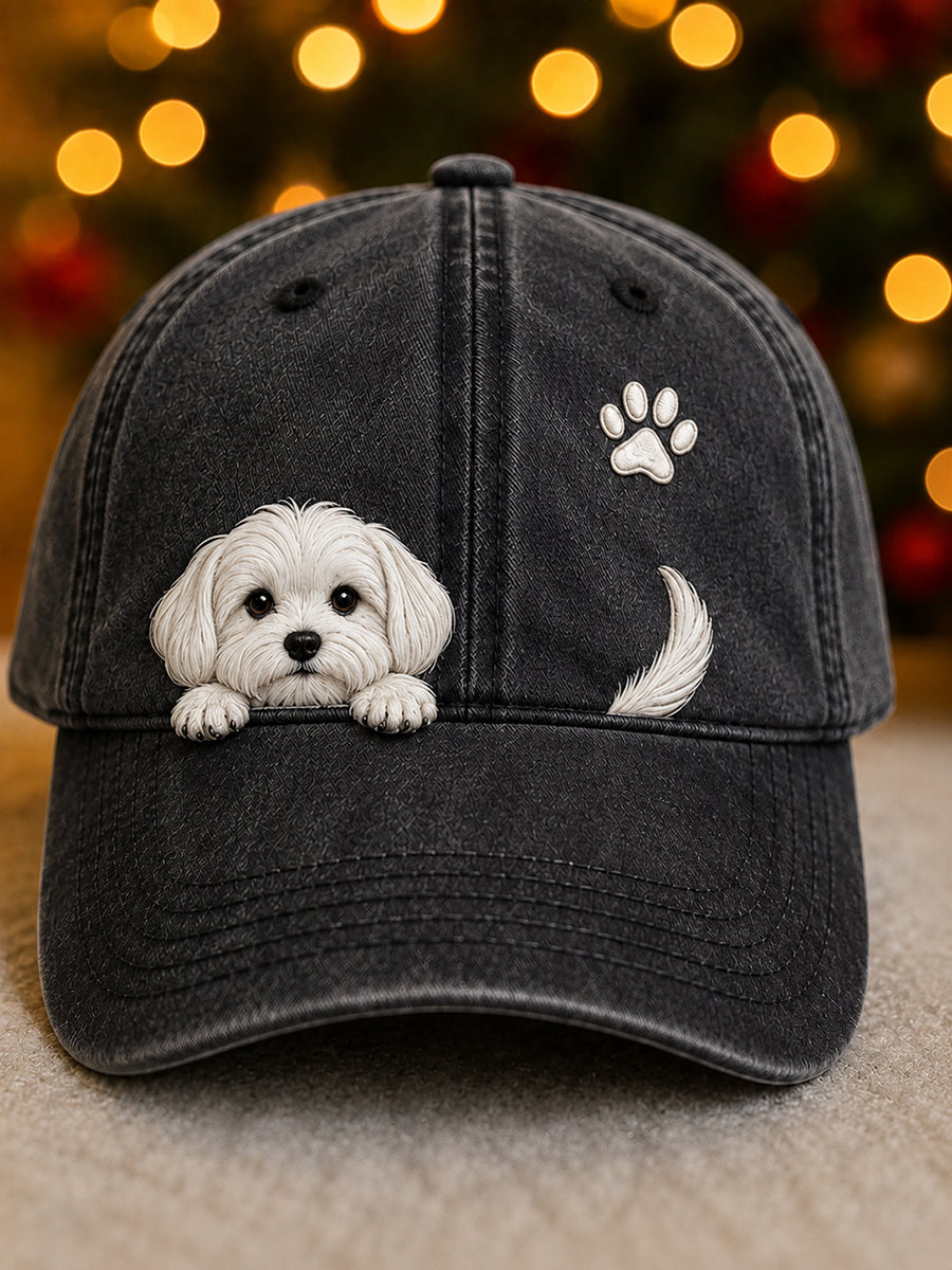 Frontansicht der schwarzen Kappe mit gewaschener Optik, weißem Hundewelpen am Schirmansatz, Pfotenabdruck und Rute vor Lichterbokeh. 3
