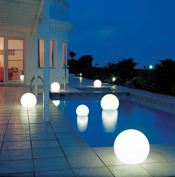 Leuchtende Kugellampen am Pool bei Nacht, moderne Außenbeleuchtung, stimmungsvolle Gartenbeleuchtung.