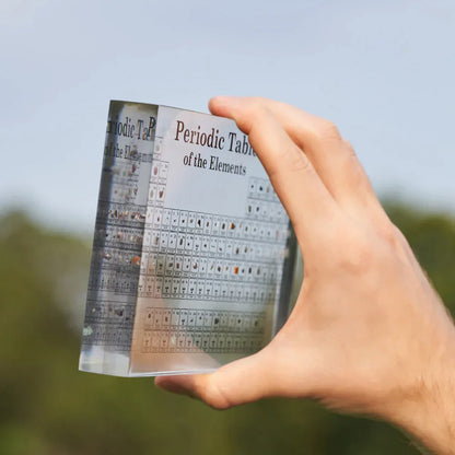 Hand hält transparenten Acrylblock mit Periodensystem der Elemente, wissenschaftliches Lehrmittel.
