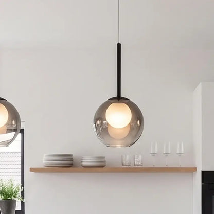 Nahaufnahme einer rauchgrauen Glaskugelleuchte mit leuchtender Innenkugel über einem Holzregal mit Tellern und Gläsern 11