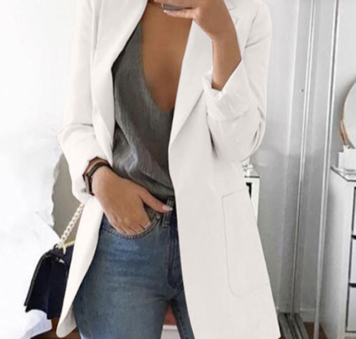 Frau in weißem Blazer, grauem Top und Jeans, modisch, elegant, Freizeitkleidung, Innenraum.