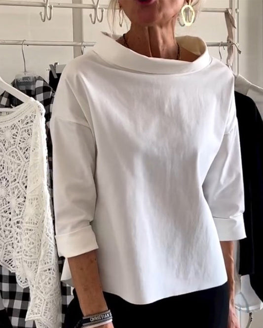 Frau in weißem, langärmligem Oberteil aus Baumwolle, modisch, elegant, vor Kleiderständer.