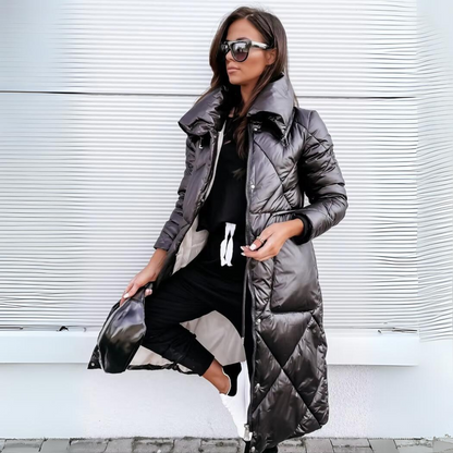Frau mit Sonnenbrille trägt den langen, schwarzen Steppmantel mit großem Kragen offen und hält dabei eine schwarze Gürteltasche in der Hand. 1