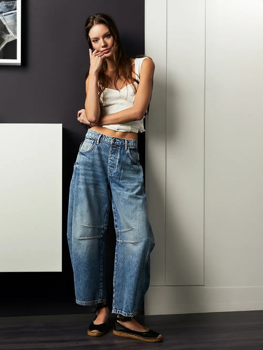 Frau in blauer Baggy-Jeans und weißem Top, lässiger Look, Modefotografie, moderne Kleidung.