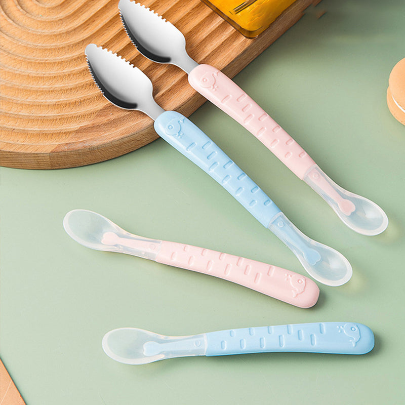 Vier Baby-Löffel und Gabeln, rosa und blau, Kunststoffgriff, auf grünem Hintergrund.