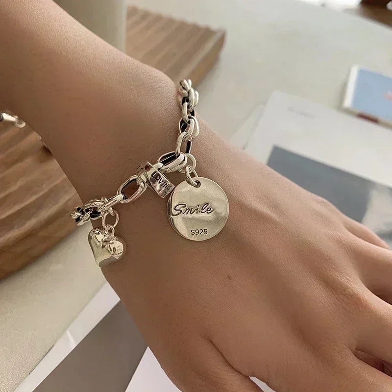 Silberarmband mit Herz- und Smile-Anhänger, S925, modisches Schmuckdesign.