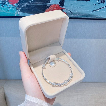 Silberarmband mit Perlen in beiger Schmuckschatulle, elegantes Design, Geschenkidee.