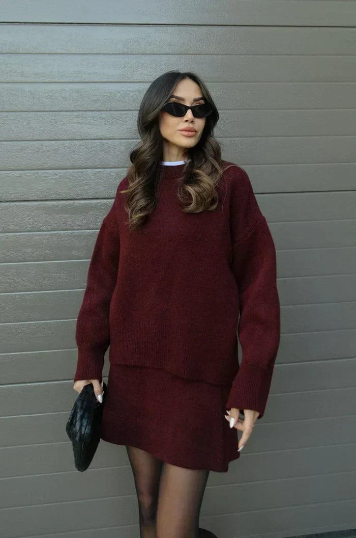 Weinrotes Strickset in Frontansicht an einem Model: oversize Pullover mit breiten Bündchen und kurzer Rock, dazu Strumpfhose. 2