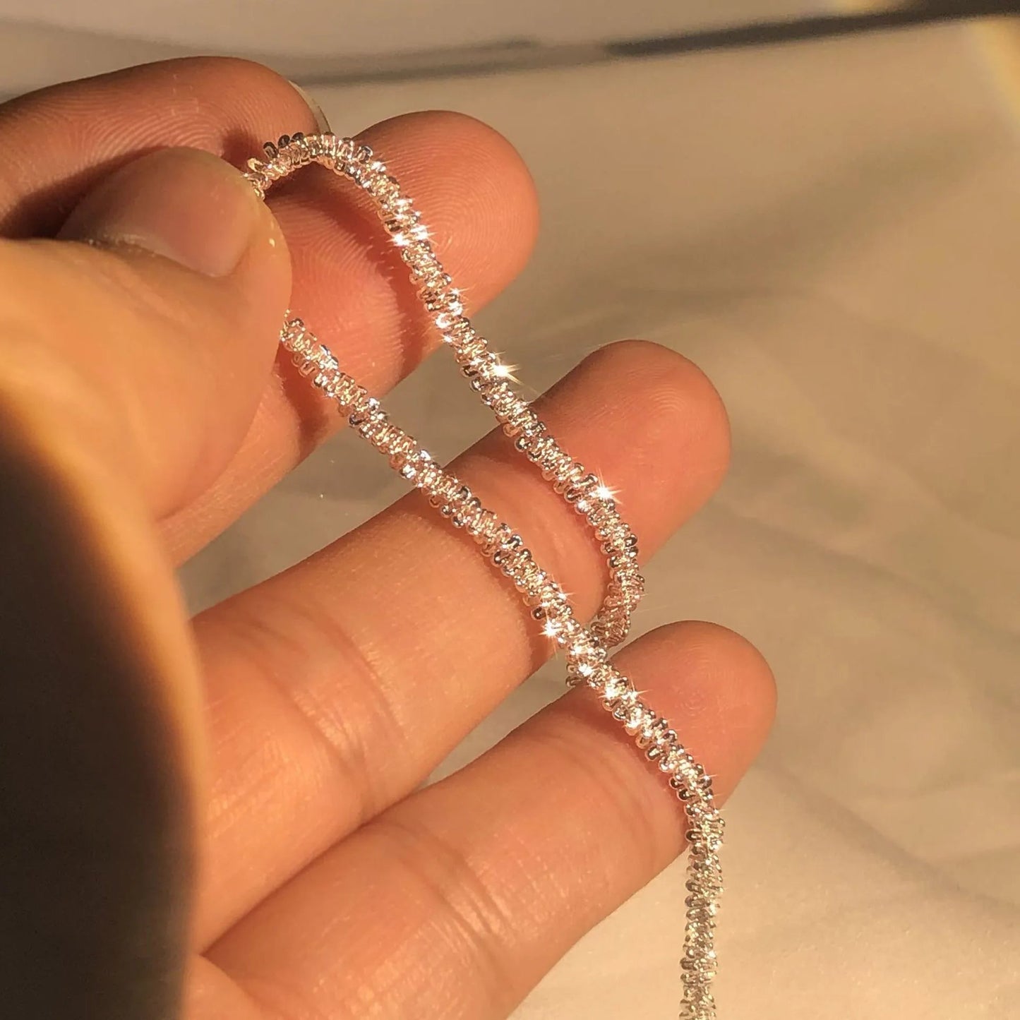 Hand hält funkelnde Diamantkette, Nahaufnahme, luxuriöses Schmuckstück, elegantes Design.
