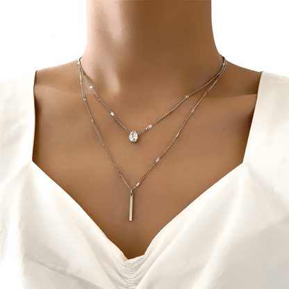Frau trägt silberne Halskette mit Tropfenanhänger, eleganter Schmuck, modisches Accessoire.
