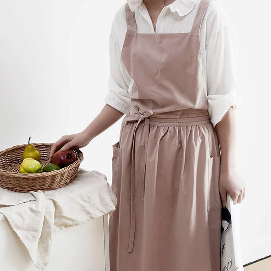 Frau in rosa Schürze mit Obstkorb, weißes Hemd, Küchenszene, Baumwolle, modern.
