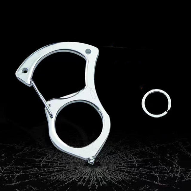 Silberner Karabiner ganz aus Metall ohne Griffauflage mit losem Schlüsselring, vor dunklem Hintergrund mit Glasbruchmuster. 4
