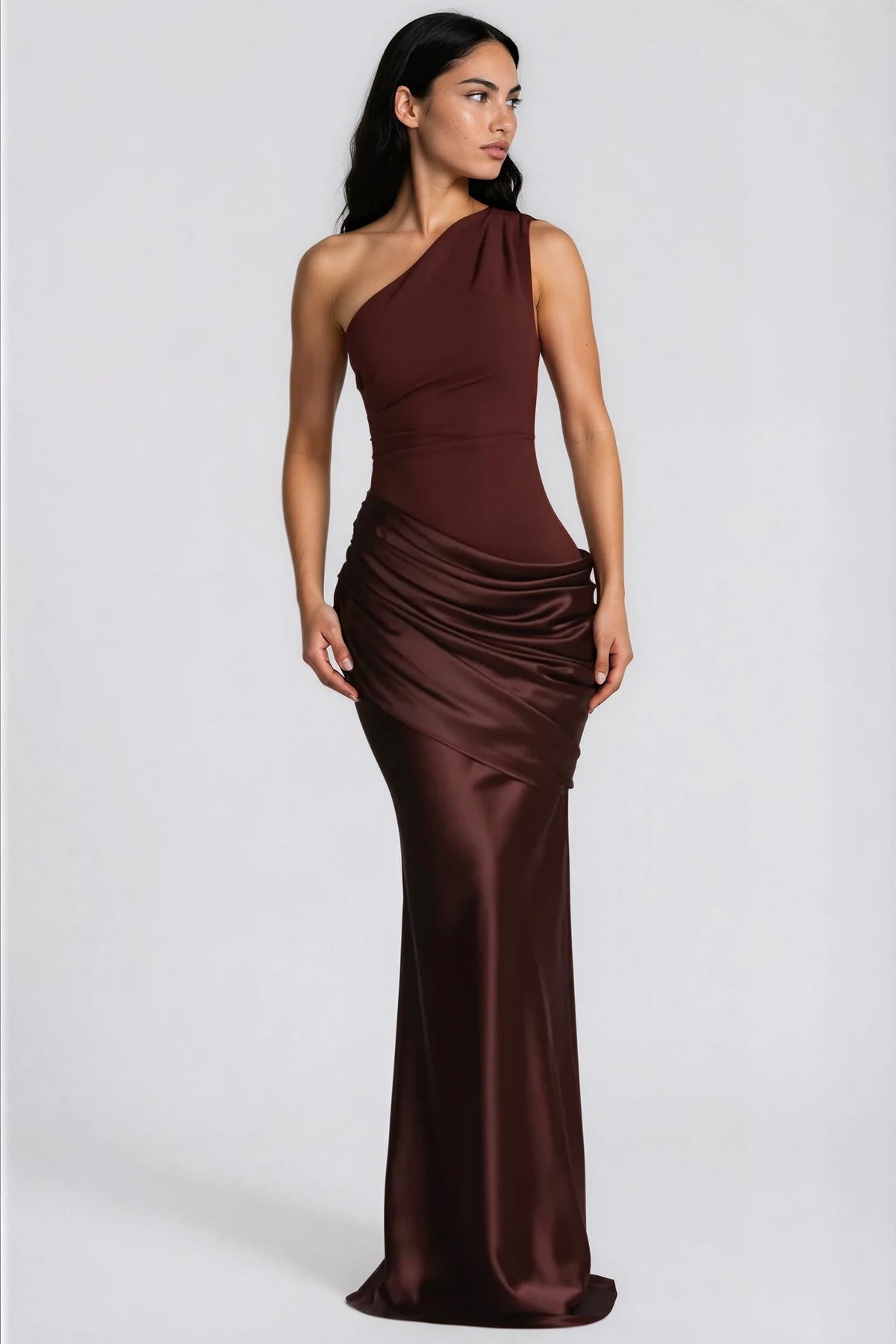 Model im dunkelbraunen Maxikleid mit einer Schulter und gerafftem Satinrock, Blick zur Seite, Ganzkörperansicht. 6