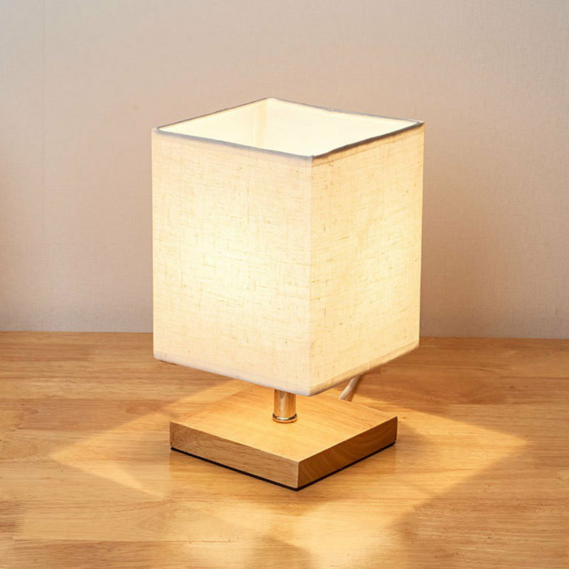 Beige Tischlampe mit quadratischem Stoffschirm auf Holzsockel, moderne Wohnraumbeleuchtung.