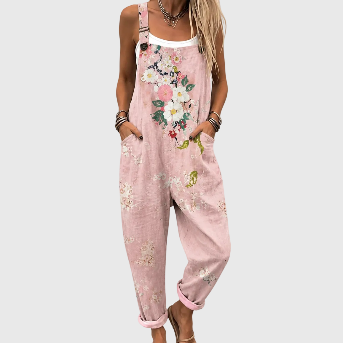 Nahaufnahme von Brust und Beinen: rosa Latzhose mit Blumenmuster, Hände in den Seitentaschen, über weißem Top getragen. 1
