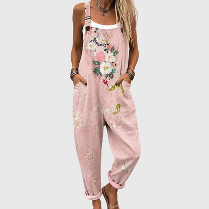 Nahaufnahme von Brust und Beinen: rosa Latzhose mit Blumenmuster, Hände in den Seitentaschen, über weißem Top getragen. 1