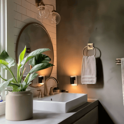 Zwei schwarze Steckdosenleuchten spenden warmes Licht in einem Badezimmer mit Waschbecken, rundem Spiegel und Zimmerpflanze 6