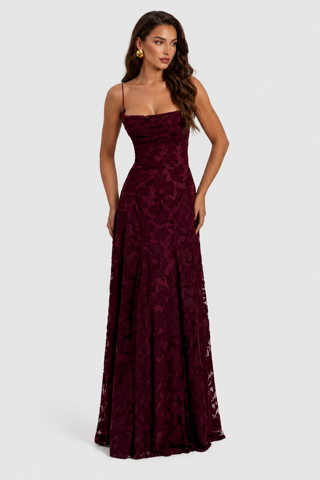 Burgunderfarbenes Kleid mit Blumenmuster, Frontansicht mit Hand an der Hüfte, drapiertem Ausschnitt und goldenem Ohrring. 9