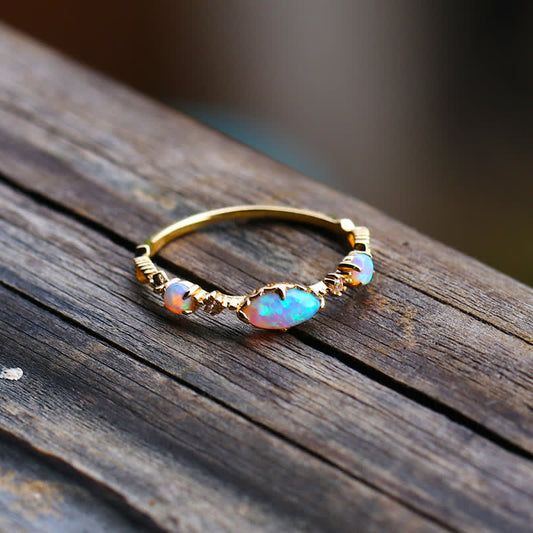 Goldener Opalring mit schimmernden Edelsteinen auf Holzoberfläche, eleganter Schmuck.
