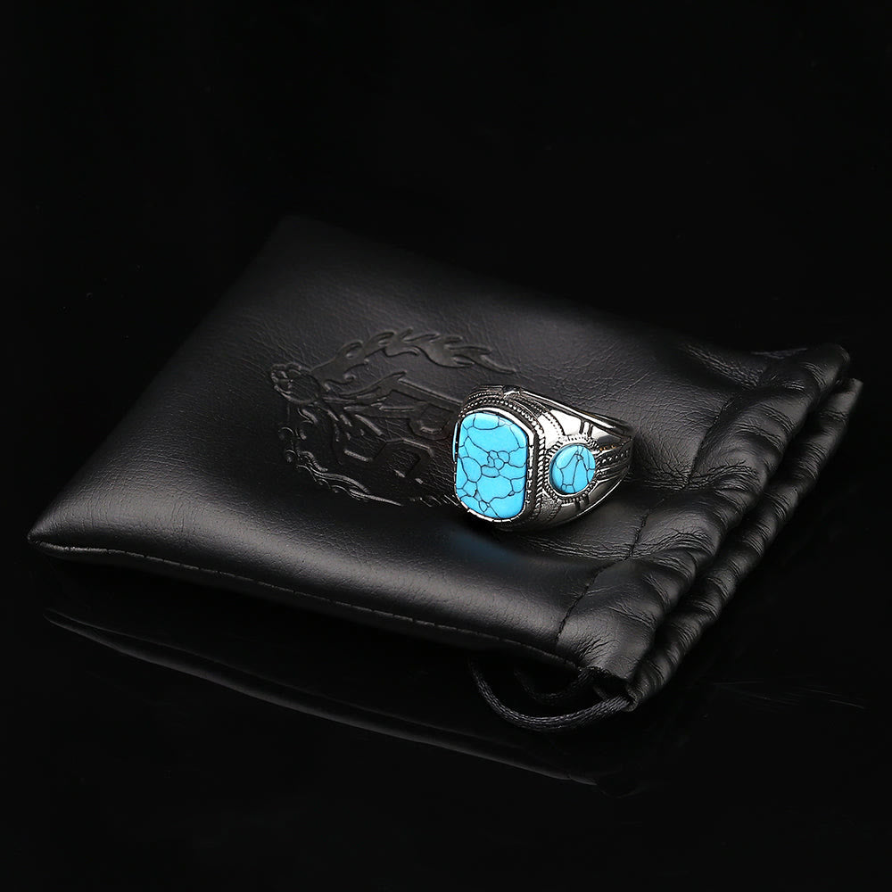 Silberner Herrenring mit blauem Türkis-Stein auf schwarzem Lederbeutel, Schmuckaccessoire.