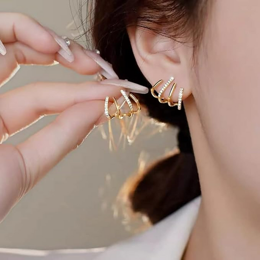 Nahaufnahme am Ohr: goldene Vierfach-Ohrstecker mit Glitzersteinen, die Hand hält den zweiten Ohrstecker hoch 2
