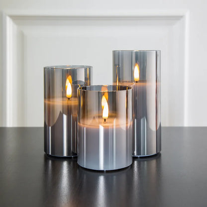 Drei silberne LED-Kerzen auf schwarzem Tisch, moderne Dekoration, reflektierende Oberfläche.