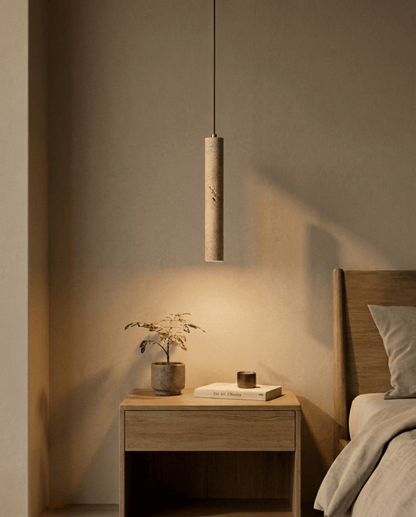 Dieselbe Pendelleuchte eingeschaltet im Schlafzimmer, warmes Licht fällt auf Nachttisch, Pflanze und Wand 2