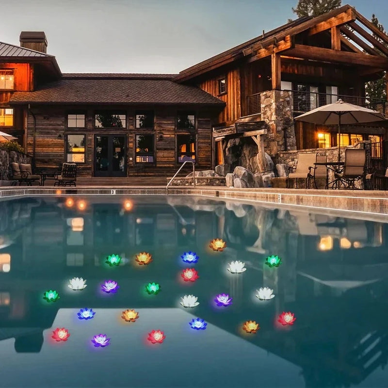 Viele bunt leuchtende Lotusleuchten schwimmen abends auf einem Pool vor einem Holzhaus 7
