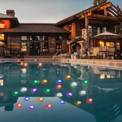 Viele bunt leuchtende Lotusleuchten schwimmen abends auf einem Pool vor einem Holzhaus 7