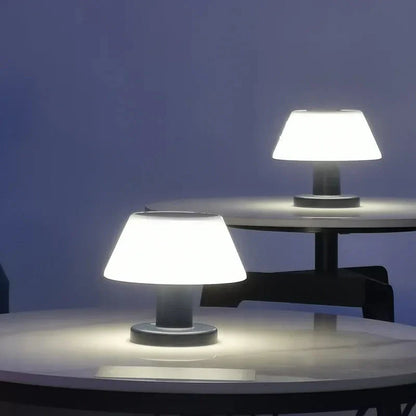 Zwei moderne LED-Tischlampen auf runden Tischen, weißes Licht, minimalistisches Design.