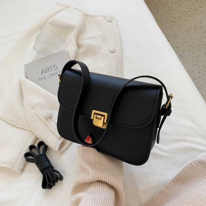Schwarze Lederhandtasche mit goldener Schnalle auf weißem Hintergrund, modisch und elegant.