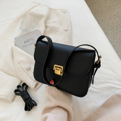 Schwarze Lederhandtasche mit goldener Schnalle auf weißem Hintergrund, modisch und elegant.
