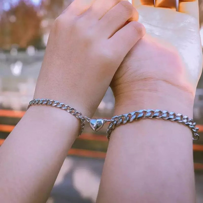 Zwei Hände mit silbernen Partnerarmbändern, Herzanhänger, Edelstahl, Freundschaftsschmuck.
