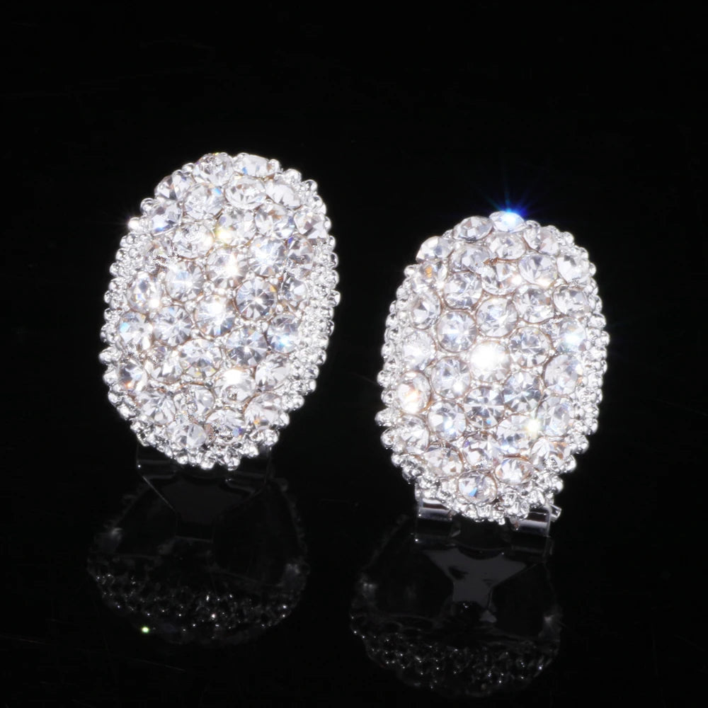 Ovale silberne Ohrringe mit Kristallsteinen, funkelnd, eleganter Schmuck, schwarzer Hintergrund.