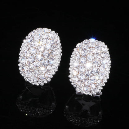 Ovale silberne Ohrringe mit Kristallsteinen, funkelnd, eleganter Schmuck, schwarzer Hintergrund.