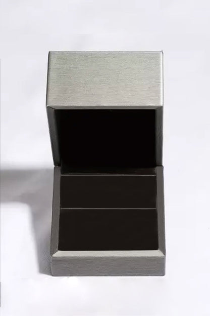 Leere silberne Schmuckschatulle, quadratisch, offen, aus Metall, auf weißem Hintergrund.