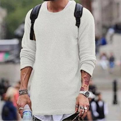 Mann in weißem Strickpullover mit Rucksack, urbaner Hintergrund, modischer Streetwear-Look.