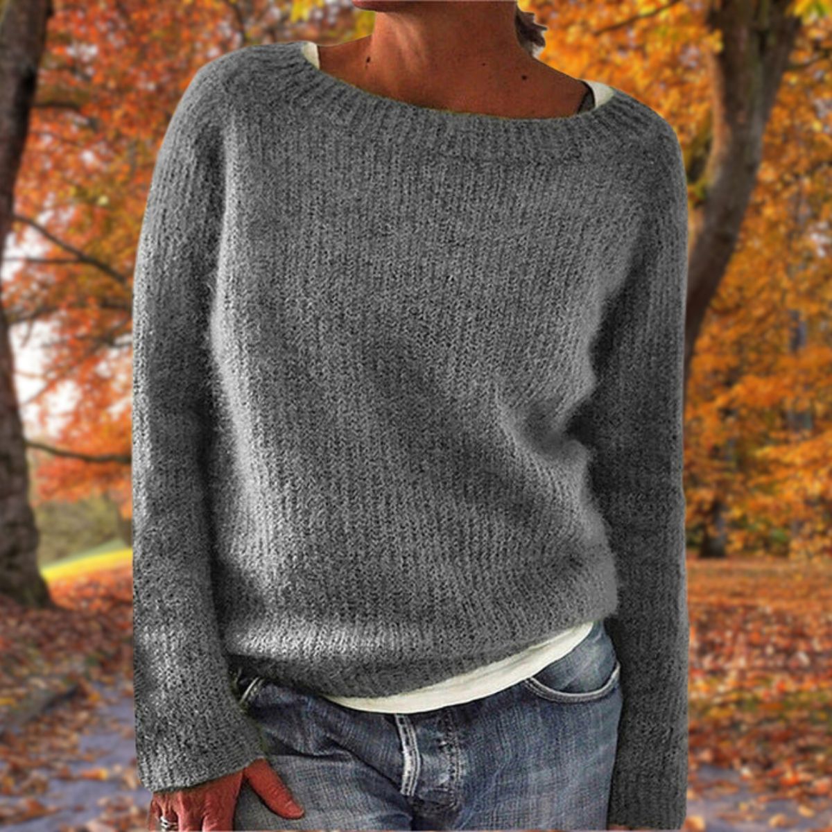 Grauer Strickpullover mit grobem Rippenstrick, von einer Frau über weißem Shirt und Jeans im Herbstwald getragen. 4