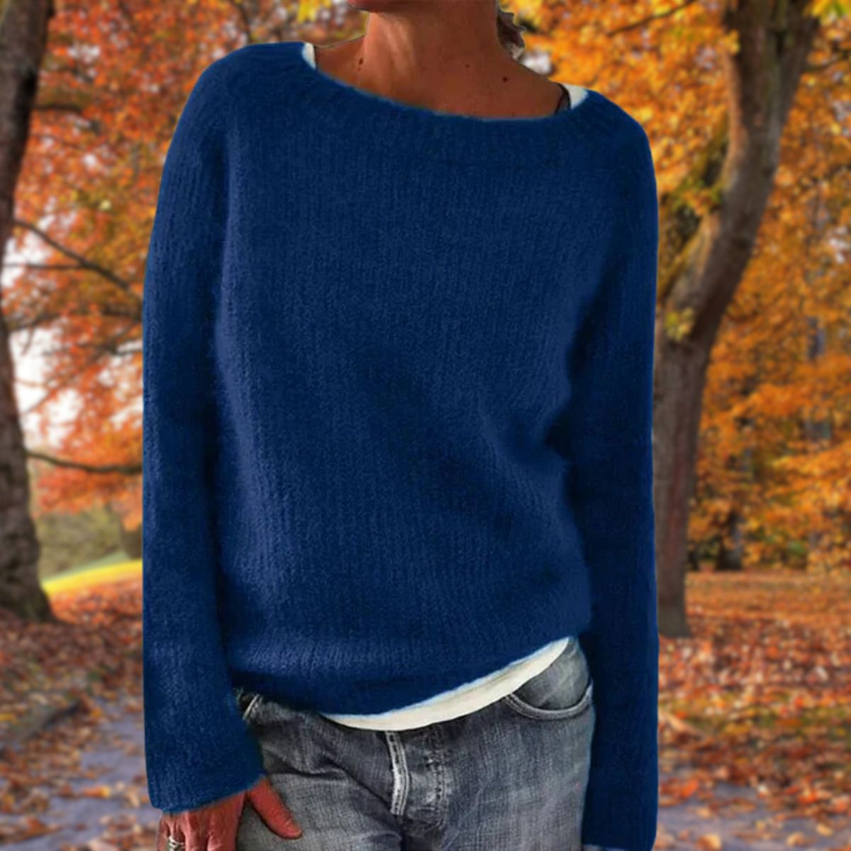 Dunkelblauer Strickpullover mit weichem Flor, kombiniert mit weißem Shirt und Jeans, im Hintergrund Herbstbäume. 3