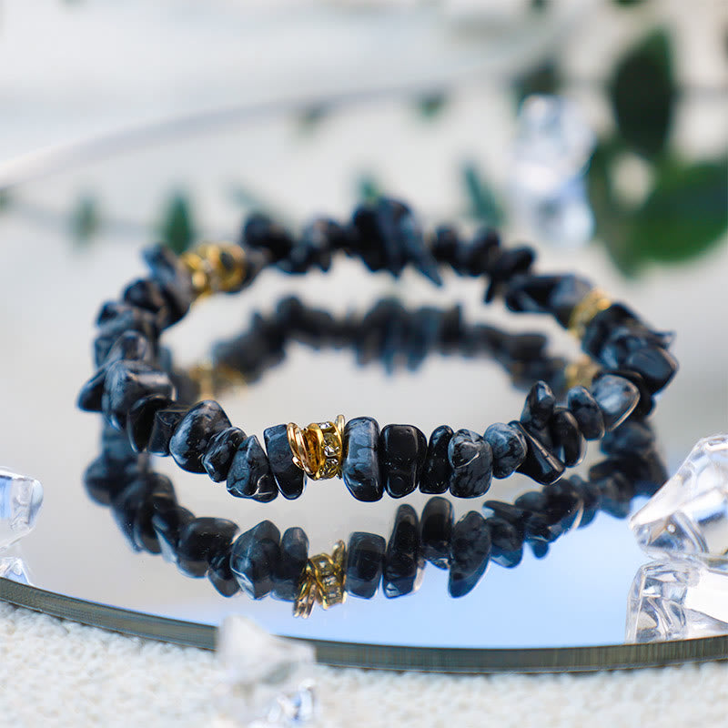 Schwarzes Edelsteinarmband mit goldenen Akzenten auf Spiegel, Schmuck, elegant, modisch.