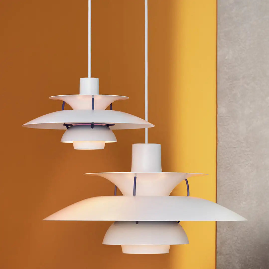 Zwei weiße Pendelleuchten, modernes Design, vor gelber Wand, skandinavischer Stil.