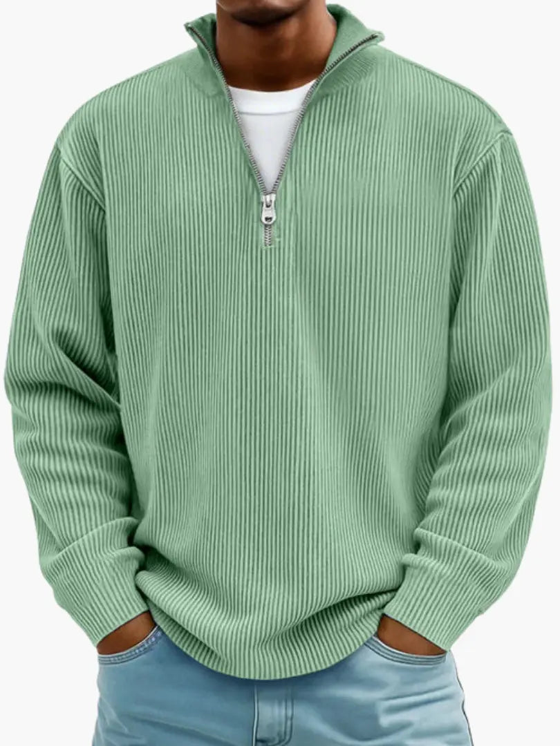 Model im gerippten Pullover mit Viertelreißverschluss in hellem Grün, lockere Passform, Hände in den Hosentaschen. 3