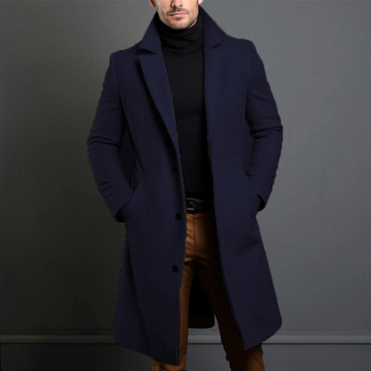 Der lange Mantel in dunklem Marineblau an einem Model, einreihig geknöpft, mit schwarzem Rollkragenpullover und brauner Hose. 4