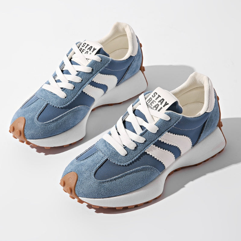 Paar blaue Wildleder-Sneaker mit weißen Streifen und Gummisohle, schräg von oben vor weißem Hintergrund 2