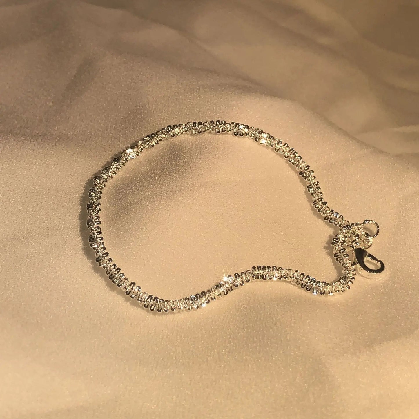 Silbernes Armband mit Zirkonia-Steinen auf beigem Stoff, funkelnd, elegantes Schmuckstück.