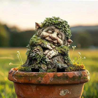 Schlafender Troll mit Blätterkranz auf Baumstumpf, in einem verwitterten Terrakottatopf mit kleinen Blüten. 17